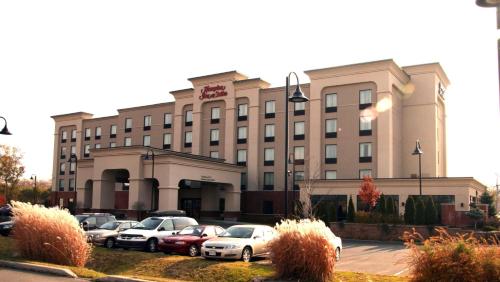 un grand bâtiment avec des voitures garées dans un parking dans l'établissement Hampton Inn & Suites Laval, à Laval