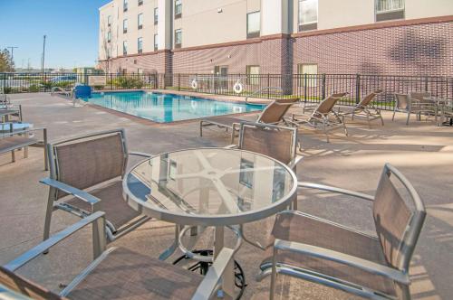 een patio met een glazen tafel en stoelen naast een zwembad bij Hampton Inn Opelousas in Opelousas