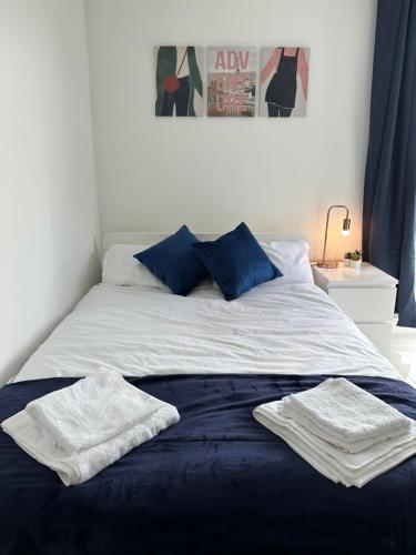 Una cama con sábanas azules y blancas y toallas. en 3 Bed Cozy Apartment - next to Leeds City Centre & University, en Headingley