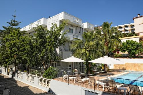 un hotel con piscina, mesas y sombrillas en Skalidis Apartments, en Tolo