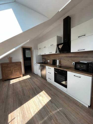 a large kitchen with white cabinets and a ceiling at Apartmány Tobias in Běšiny