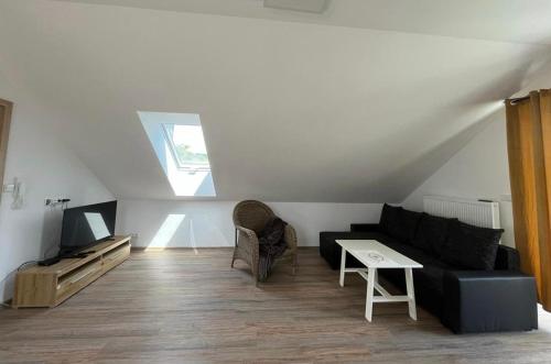 a living room with a black couch and a tv at Apartmány Tobias in Běšiny