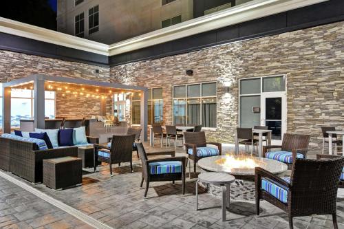 een patio met tafels en stoelen en een bakstenen muur bij Homewood Suites By Hilton Lynchburg in Lynchburg