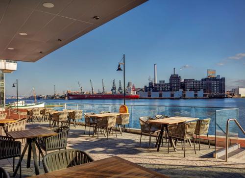 d'une terrasse avec tables et chaises et vue sur l'eau. dans l'établissement Canopy By Hilton Baltimore Harbor Point - Newly Built, à Baltimore