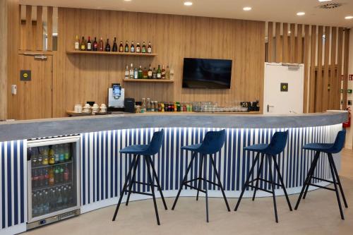 um bar com bancos azuis num bar em Hampton By Hilton Poznan Swarzedz em Swarzędz