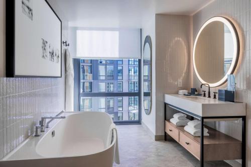 y baño con bañera, lavabo y espejos. en The Morrow Washington Dc, Curio Collection By Hilton, en Washington