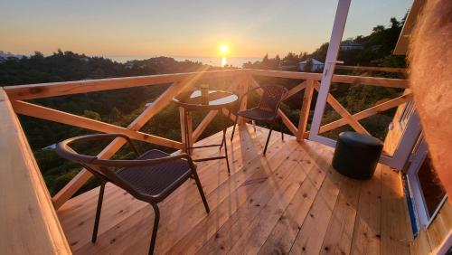 2 Stühle und ein Tisch auf einer Terrasse mit Sonnenuntergang in der Unterkunft VILLA GANTIADI in Batumi