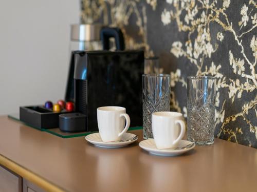 Un mostrador con dos tazas y dos vasos. en Sia Boutique Aparthotel, en Sibiu