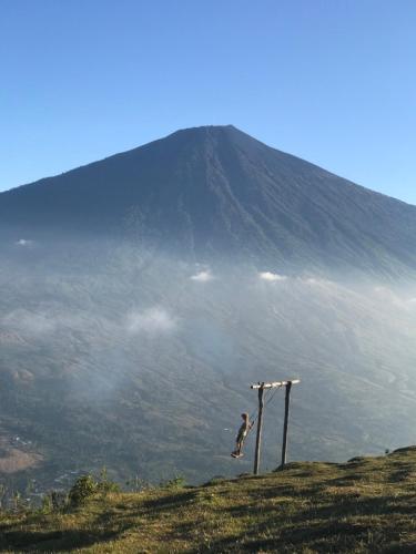 a person is jumping off of a mountain at Rinjani Houseboon in Senaru