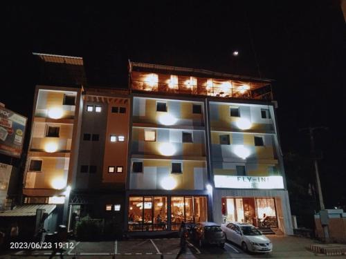 IvatoFLY INN Madagascar HOTEL - Navette GRATUITE H24 - à 300m de l'Aéroport International Ivato-Antananarivo的一座高大的建筑,前面有一辆汽车