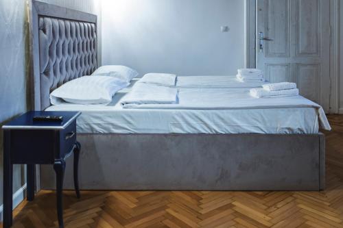 1 cama con sábanas blancas y almohadas en una habitación en Sia Boutique Aparthotel, en Sibiu