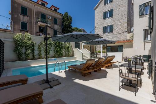 a patio with chairs and an umbrella next to a pool at Sperone Hotel in Split