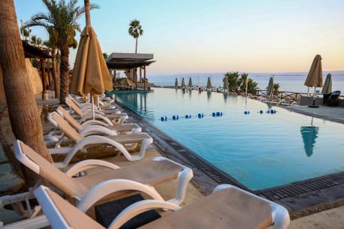 una piscina con sedie a sdraio e ombrelloni di O Beach Hotel & Resort a Sowayma