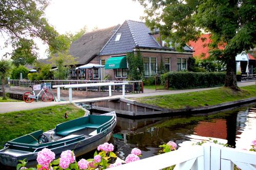 a boat is docked at a house on a canal at De Galeriet Giethoorn in Giethoorn