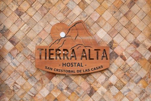 圣克里斯托瓦尔-德拉斯卡萨斯Tierra Alta Hostal的瓷砖地板上的酒店木标志