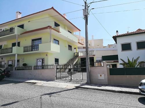 a white house with a fence in front of it at Casa Fonte Nova in Nazaré