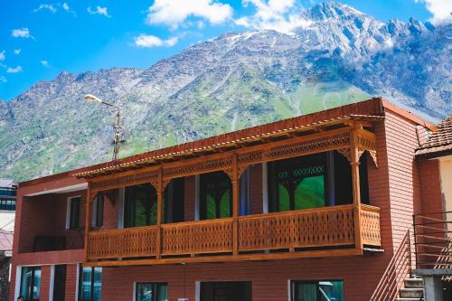 - un bâtiment avec un balcon donnant sur la montagne en arrière-plan dans l'établissement Fiten house, à Kazbegi