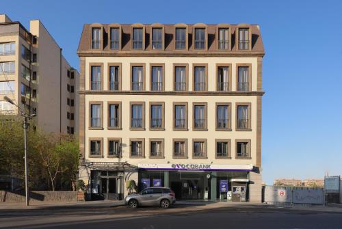 un edificio con un'auto parcheggiata di fronte di Apricot Hotel Yerevan a Yerevan