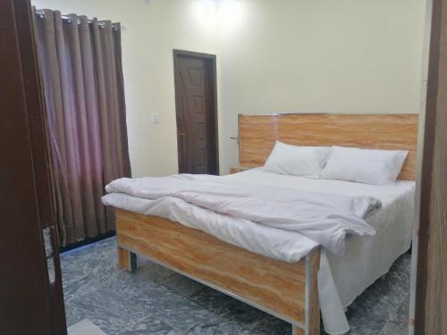 a bedroom with a bed with a wooden headboard at Navid's Holiday Resort and Hotel, Murree in Ghora Gali