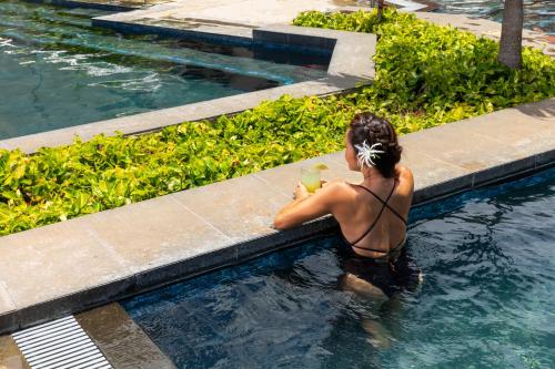 een vrouw in een zwembad met een drankje bij Sheraton Kauai Coconut Beach Resort in Kapaa