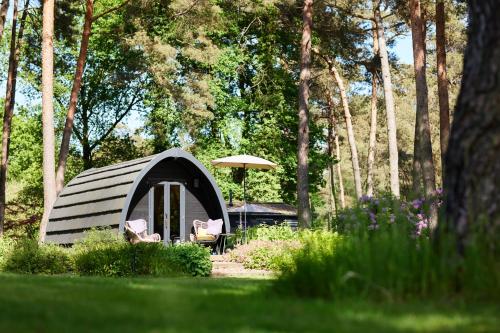 een kleine tent met twee stoelen en een paraplu bij KampinaStaete, hippe cottages midden in natuurgebied de Kampina Oisterwijk in Oisterwijk