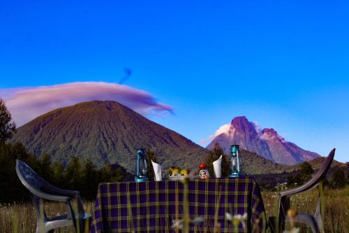 une table de pique-nique avec une montagne en arrière-plan dans l'établissement Under Volcanoes View Guest House, à Nyarugina