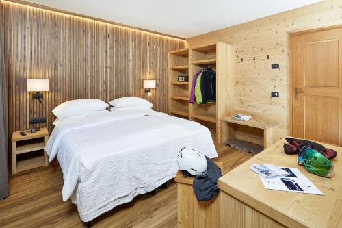 um quarto com uma cama branca e paredes de madeira em Hotel Garni dello Sportivo em Madonna di Campiglio