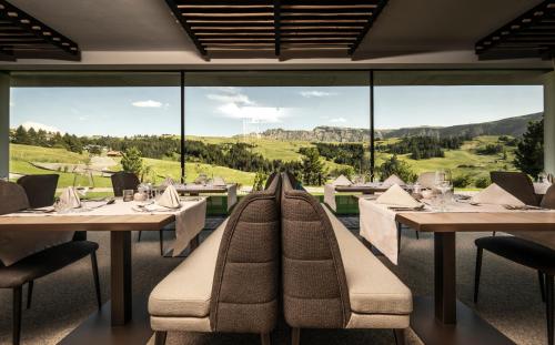 un restaurante con mesas y sillas y una gran ventana en Hotel Schmung, en Alpe di Siusi