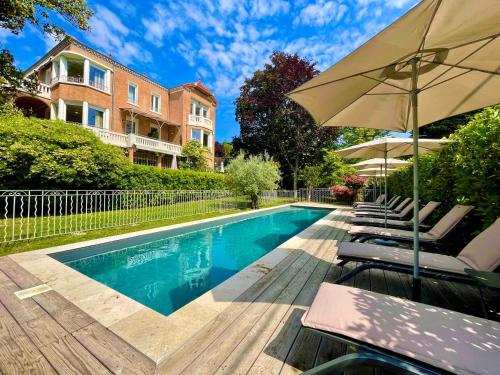 een zwembad met stoelen en een parasol bij Villa Elisa M in Aubenas