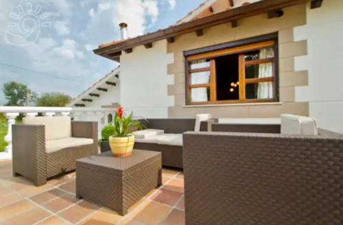 a patio with wicker furniture and a house at Apartamentos Nel I in Santillana del Mar