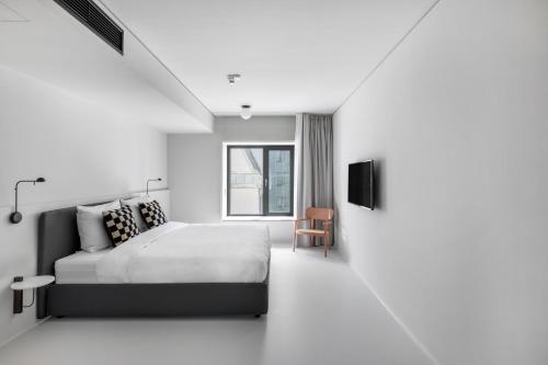 a white bedroom with a bed and a tv at Numa I Savi Rooms & Apartments in Berlin