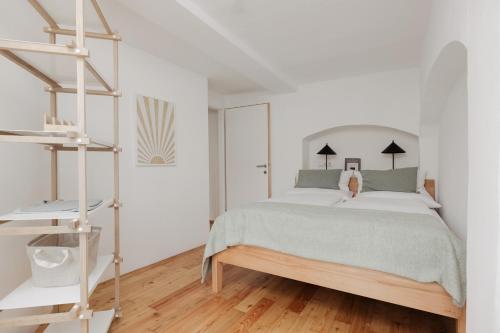 - une chambre blanche avec un lit et du parquet dans l'établissement Das Grüne Haus - Boutique Apartments ecofriendly, à Innsbruck