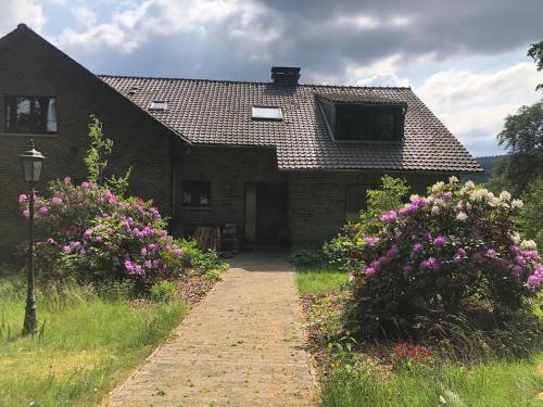 una casa con fiori rosa di fronte di Le refuge de Kila a Waimes