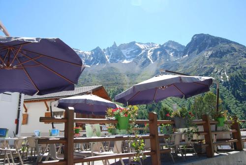 um restaurante com mesas e guarda-sóis com montanhas ao fundo em Hotel du Pigne em Arolla