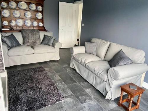 ein Wohnzimmer mit 2 weißen Sofas und einem Tisch in der Unterkunft Bryn Mair cottage overlooking Snowdon in Caernarfon