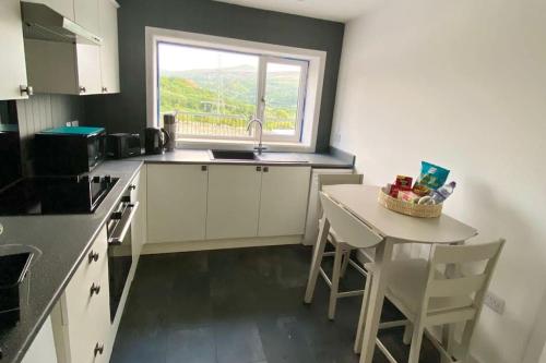 eine Küche mit einem Waschbecken, einem Tisch und einem Fenster in der Unterkunft Bryn Mair cottage overlooking Snowdon in Caernarfon