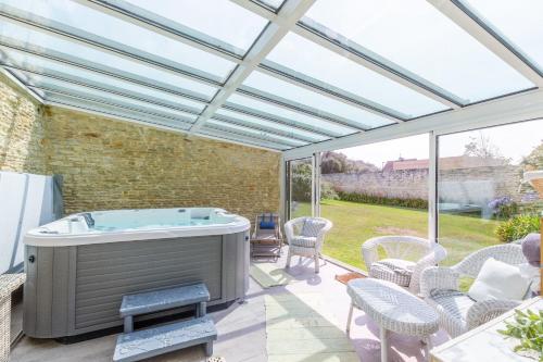 einen Whirlpool auf einer Terrasse mit Glasdach in der Unterkunft Villa de la Plage - à Ver sur Mer in Ver-sur-Mer