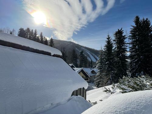 una panchina coperta di neve con il sole nel cielo di GARAGE Harrachov a Harrachov