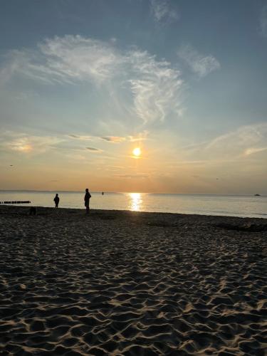 duas pessoas de pé na praia ao pôr do sol em Villa Nadzieja em Międzyzdroje