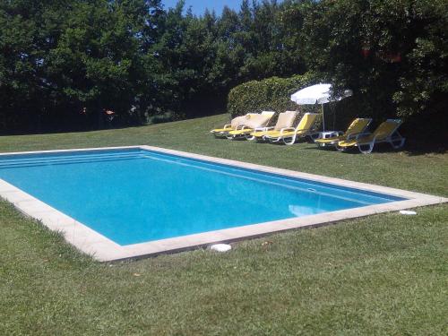 una piscina en la hierba con sillas y sombrilla en Quinta da Fonte Arcada, en Paço de Sousa