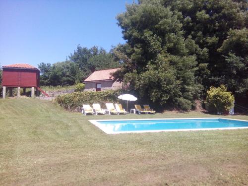 una piscina en un patio con sillas y sombrilla en Quinta da Fonte Arcada, en Paço de Sousa