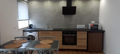 a kitchen with a table with chairs and a sink at Apartamentos Naturalis in Vila Nova de Milfontes