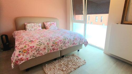 - une chambre avec un lit avec une couette rose et une fenêtre dans l'établissement Mooi vakantiehuis tussen Breda, Antwerpen, Gent & Hasselt, à Anvers