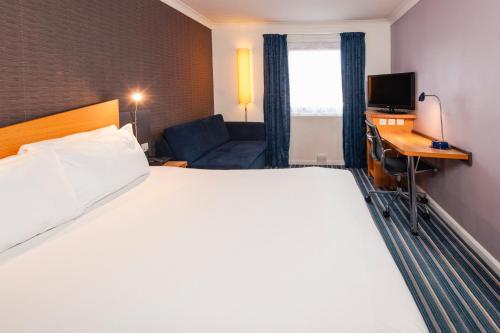 a hotel room with a large bed and a couch at Holiday Inn Express Southampton West, an IHG Hotel in Southampton