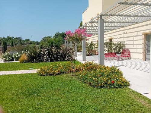 - un jardin avec 2 chaises et des fleurs dans la cour dans l'établissement Torre Assunta Masseria, à Gallipoli