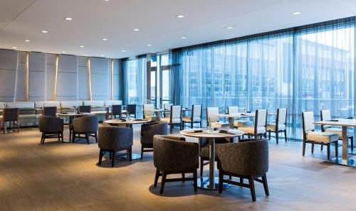 un ristorante con tavoli, sedie e ampie finestre di AC Hotel Cincinnati at Liberty Center a West Chester