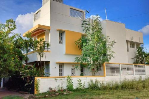 un edificio bianco e giallo con alberi di fronte di Athreyas@60/A a Mysore