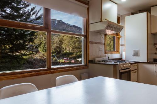 eine Küche mit einem Tisch und einem großen Fenster in der Unterkunft BOG Angostura Apartments in Villa La Angostura