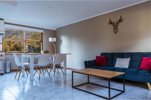 ein Wohnzimmer mit einem blauen Sofa und einem Tisch in der Unterkunft BOG Angostura Apartments in Villa La Angostura