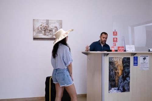 una mujer usando un sombrero de vaquero parada en un mostrador en Mare Sole, en San Teodoro